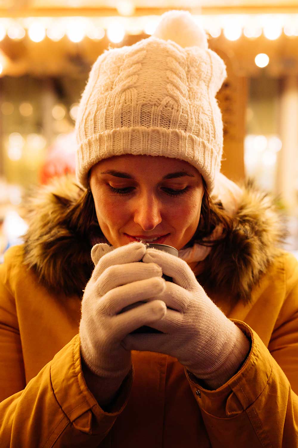 Weihnachtsmarkt-bad-wimpfen_Tassen_252 junge Frau hält eine Tasse Glühwein in den Händen und wärmt ihre Hände